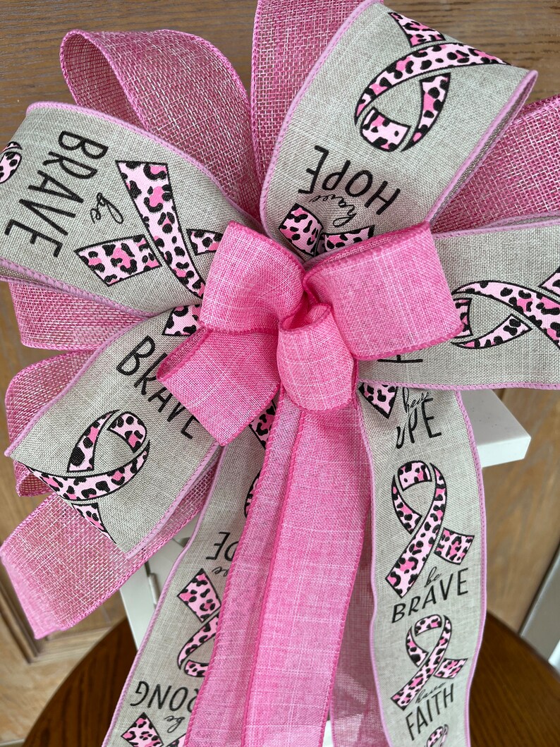 May include: Pink and beige ribbon with a pink leopard print and the words "Be Brave", "Hope", "Be Strong", "Be Brave", and "Faith" printed on it.