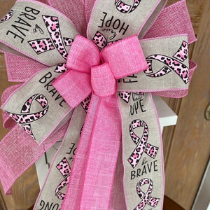 May include: Pink and beige ribbon bow with a pink leopard print and the words "Be Brave", "Have Hope", "Have Faith" and "Be Strong".