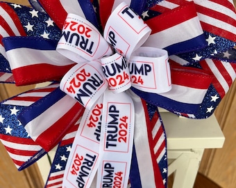 May include: A red, white, and blue bow with glitter stars and white ribbon with the text "TRUMP 2024" repeated on it.