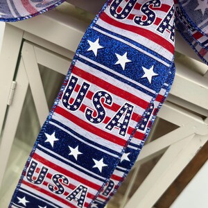 May include: Red, white, and blue ribbon with the word "USA" printed on it. The ribbon is decorated with stars and stripes.