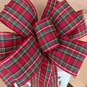 May include: A large red, green, yellow, and white plaid bow with a long tail. The bow is tied on a white lantern.
