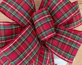 May include: A large red, green, yellow, and white plaid bow with a long tail. The bow is tied on a white lantern.