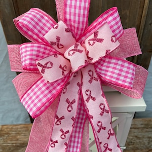 May include: Pink and white gingham ribbon bow with a pink ribbon tail featuring a pink glitter ribbon design of multiple pink ribbons.