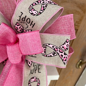 May include: Pink and brown ribbon with a leopard print design and the words "Have Hope" on a burlap background.