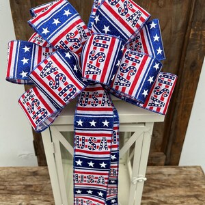 May include: A red, white, and blue bow with the word "USA" printed on it. The bow is tied around a white lantern.