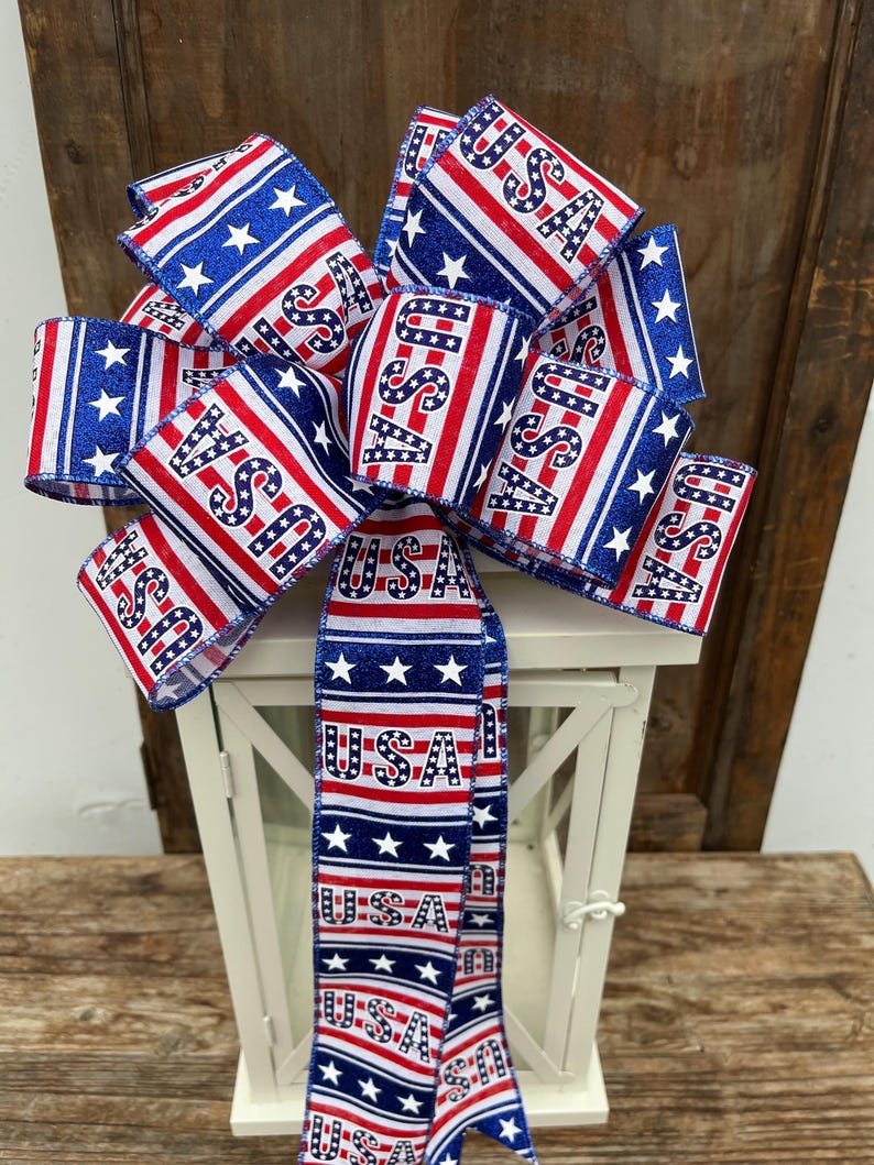 May include: A red, white, and blue bow with the word "USA" printed on it. The bow is tied around a white lantern.