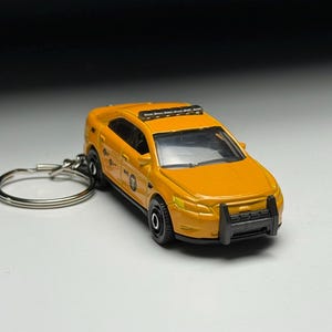 以下が含まれることがあります： 黄色の玩具タクシーキーホルダー。 ミニカーは黒いタイヤ、黒いフロントバンパー、黒いルーフラックを備えています。 キーホルダーリングはシルバーです。