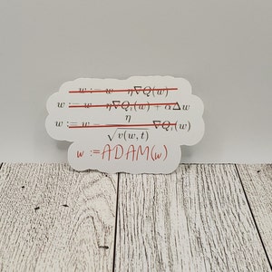 Könnte beinhalten: Ein weißer Aufkleber mit einer mathematischen Formel für den ADAM-Optimierungsalgorithmus. Die Formel ist in schwarzer Tinte geschrieben, wobei eine rote Linie durch die oberste Gleichung gezogen ist. Der untere Teil des Aufklebers lautet "w := ADAM(w)" in roter Tinte.
