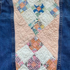 May include: A denim jacket with a quilted back panel. The panel features a patchwork design with squares of various patterned fabrics in shades of blue, pink, orange, and white. The jacket is a medium wash denim.