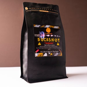Może przedstawiać: Czarny worek z kawą z napisem "BUCKSHOT" i "It's Like A Shot In The Face!". Worek posiada etykietę ostrzegawczą z grafiką pocisku. Worek jest zamknięty zamkiem błyskawicznym.