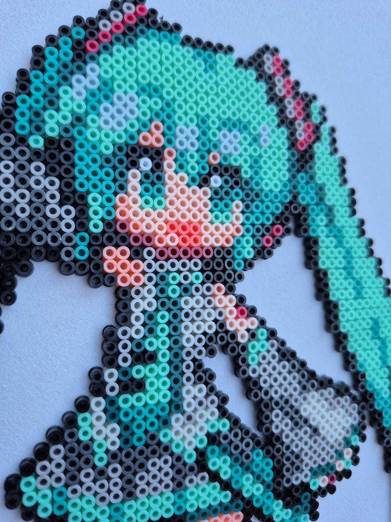May include: Pixel art portrait of a character with turquoise hair, created with colorful plastic beads. The artwork features a detailed face with pink and red accents, set against a white background. The beads are arranged to form a recognizable anime-style image.