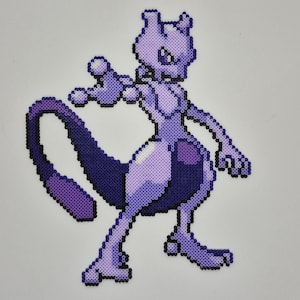 May include: A pixelated image of the Pokémon Mewtwo, rendered in shades of purple and lavender. The artwork is created using small, evenly spaced beads, giving it a textured appearance. The figure is in a dynamic pose, with one arm extended.