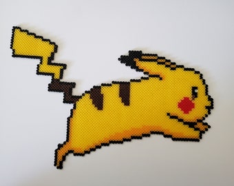 May include: A pixelated Pikachu figure made from yellow, black, brown, and red beads. The figure is in a running pose with its tail extended. The background is a plain white surface.