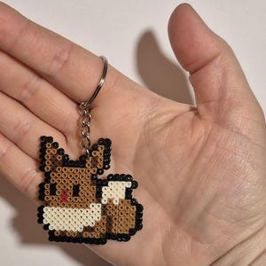 May include: A brown and white beaded keychain shaped like a fox with a silver key ring.