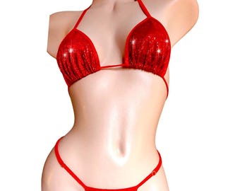 Può includere: Un set bikini rosso con paillettes. La parte superiore è un modello all'americana con coppe a triangolo. La parte inferiore è uno stile perizoma. Il bikini è esposto su un busto di manichino su sfondo bianco.