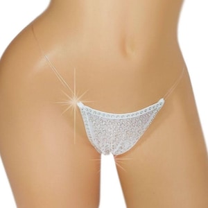 May include: White thong underwear with a delicate, lacy design and sparkling embellishments. The thong features a low-rise cut and thin, clear straps. The underwear is displayed on a mannequin against a white background.