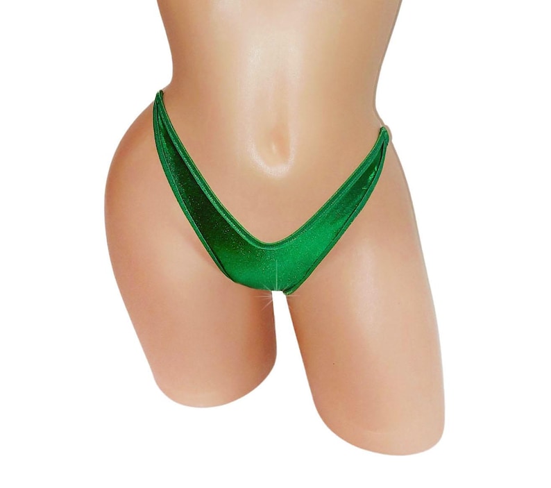 May include: A close-up of a shiny, emerald green bikini bottom. The high-cut design features a V-shaped front and a narrow back, showcasing a minimalist style. The fabric has a subtle sheen, reflecting light.