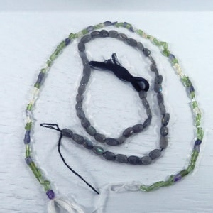 May include: Two strands of beads, one with oval-shaped grey labradorite beads and the other with a mix of green, purple, and clear beads.