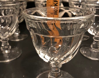 May include: Set of six clear glass drinking glasses with a swirl design. The glasses have a wide bowl and a tall stem.