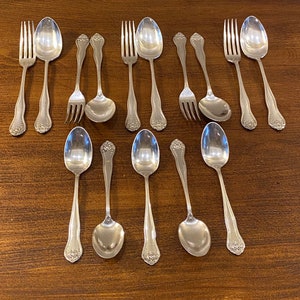 Peut inclure: Un ensemble de 12 couverts en argent plaqué, comprenant des fourchettes et des cuillères. Les couverts ont un design orné avec un motif floral.
