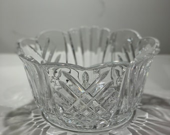 May include: A clear glass bowl with a scalloped rim and intricate cut-glass design. The bowl is made by Waterford.