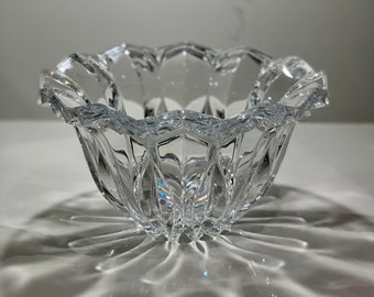 May include: A clear glass bowl with a starburst design. The bowl is sitting on a white surface and casting a shadow.