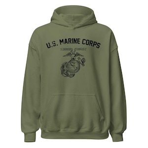 May include: An olive green hooded sweatshirt featuring a black graphic print on the chest. The text U.S. MARINE CORPS is arched above the Eagle, Globe, and Anchor emblem, which includes a banner with the Latin phrase SEMPER FIDELIS.