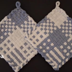 May include: Two square potholders featuring a woven checkerboard pattern in white and light blue yarn. Each potholder has a small loop at the top corner for hanging. The text White Hydrangea is printed in white on the lower left side of the image.