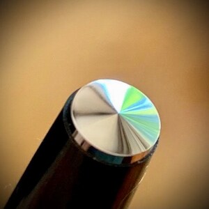 May include: Close-up of a silver pen cap with a textured, diamond-shaped pattern.