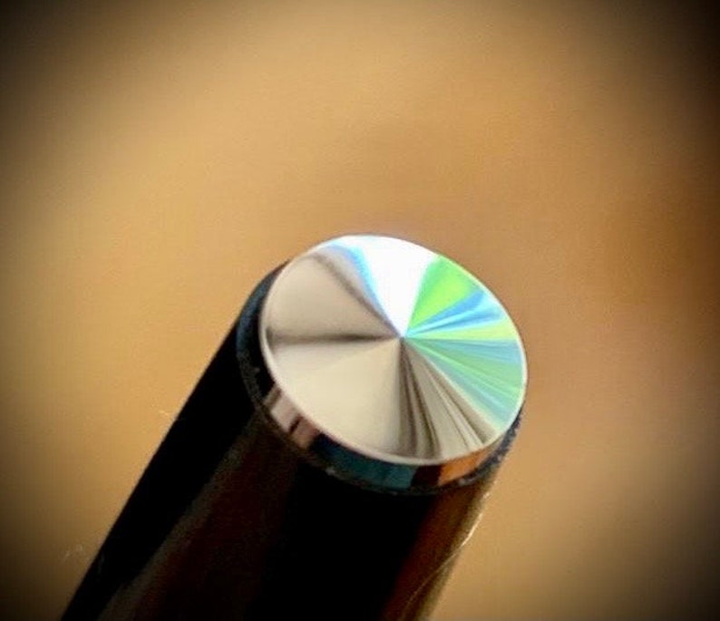 May include: Close-up of a silver pen cap with a textured, diamond-shaped pattern.