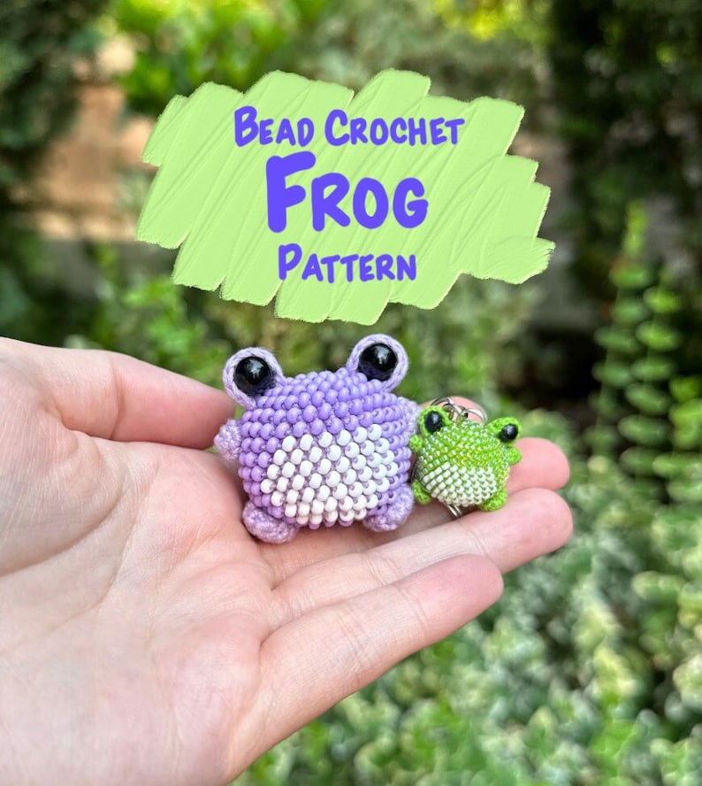 May include: A close-up of two beaded crochet frog figures. One is a larger lavender frog with white accents, and the other is a smaller green frog with white accents. The image includes the text "Bead Crochet Frog Pattern" in a green box.