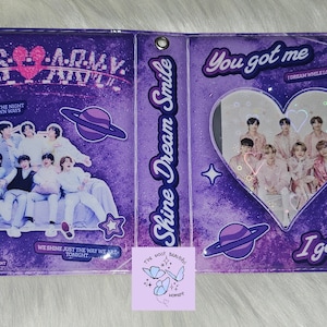 Peut inclure: Un carnet à paillettes violet et blanc avec une fenêtre en forme de cœur montrant une photo d'un groupe de garçons. Le carnet porte les inscriptions "Shine Dream Smile" et "You got me" sur la couverture avant. La couverture arrière porte les inscriptions "BTS ARMY" et une photo du groupe de garçons assis sur un canapé.