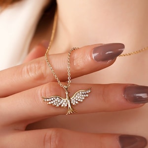 May include: A gold necklace with a small bird pendant adorned with clear cubic zirconia stones.