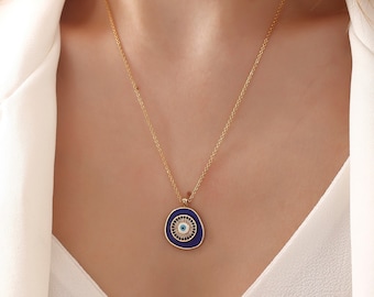 May include: A gold chain necklace with a blue and white evil eye pendant. The pendant is a rounded oval shape with a gold rim.