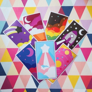 May include: Set of 8 colorful space-themed stickers with various designs, including a shooting star, planets, a rocket ship, and a galaxy. The stickers are printed on white cardstock and have a glossy finish.