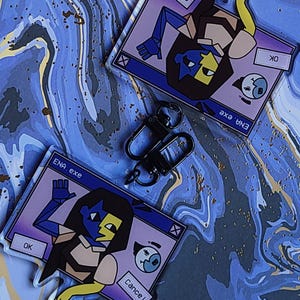 May include: Two ENA.exe acrylic keychains with black carabiner clips. The keychains feature a cartoon character in a window design with the text "ENA.exe", "OK", and "Cancel". The background is a blue and white marbled pattern.