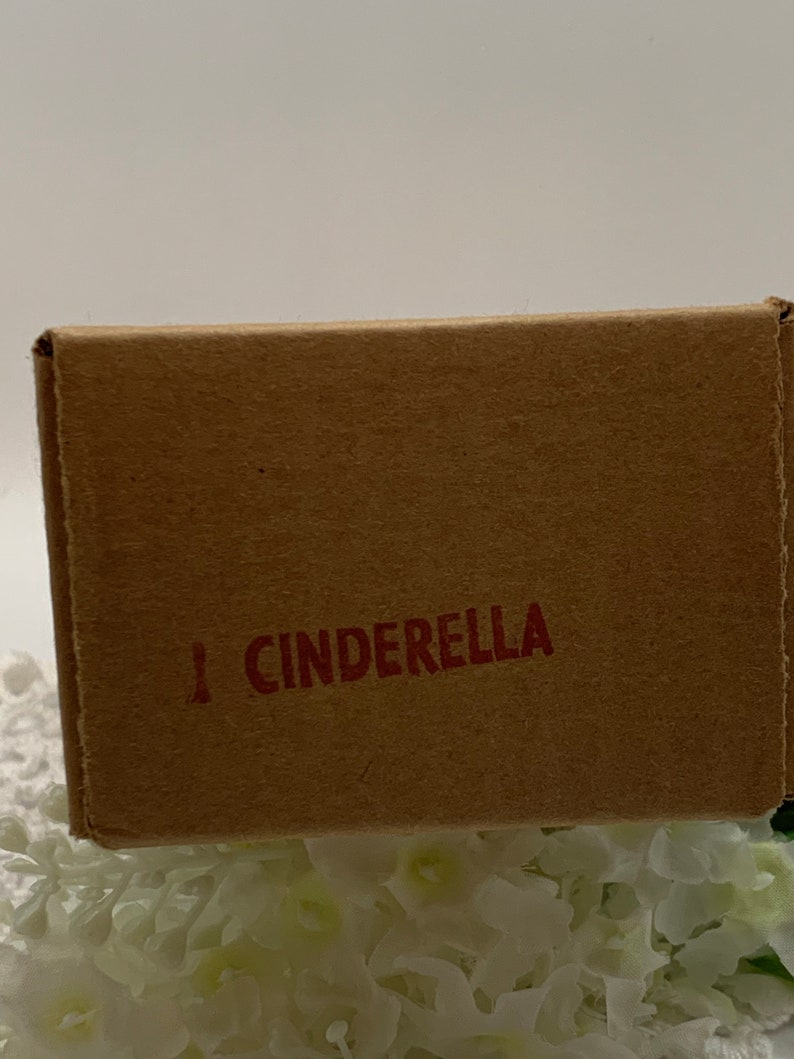 Op de afbeelding: Een bruine kartonnen doos met het woord "CINDERELLA" in rode letters.