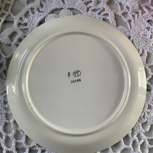 May include: White ceramic plate with a gold rim and a gold inscription that reads "PY JAPAN".