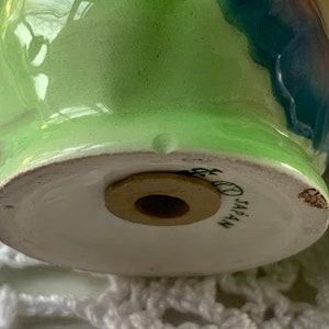 May include: Green and blue ceramic salt or pepper shaker with a wooden stopper. The bottom of the shaker has the words "JAPAN" printed on it.
