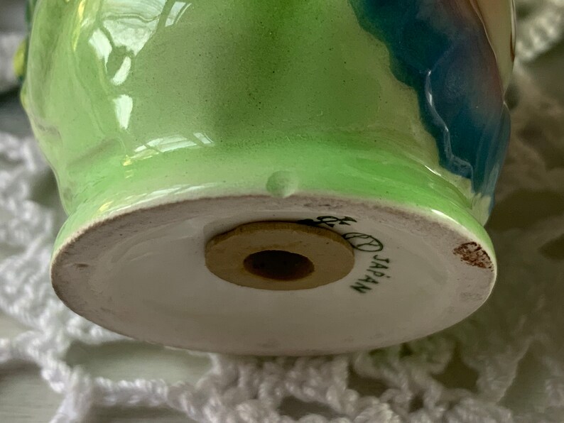 May include: Green and blue ceramic salt or pepper shaker with a wooden stopper. The bottom of the shaker has the words "JAPAN" printed on it.