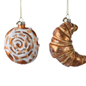 Può includere: Due decorazioni natalizie in vetro. Una è una palla rotonda arancione con un disegno a spirale bianco. L'altra è un ornamento a forma di croissant in arancione e oro, con dettagli glitterati. Entrambi hanno cordini dorati per appenderli.