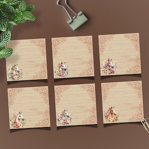 May include: Six square notepads with a watercolor horse head design. Each notepad features a horse adorned with a floral crown, set against a lined, wood-grain background. Decorative floral corner accents frame the design. The pads are arranged on a brown surface.