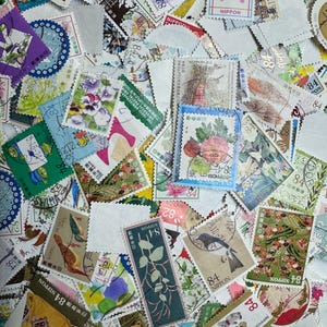 May include: A large collection of assorted Japanese postage stamps featuring various designs including flowers, birds, animals, and cartoon characters. Each stamp displays the text Nippon and a numerical value such as 84 or 94, with serrated edges.