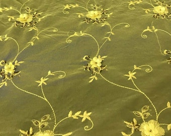 May include: Olive green sheer fabric with yellow embroidered floral designs. The fabric has a delicate, airy feel and is perfect for creating garments or home decor.