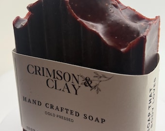 May include: A dark brown bar of soap with a white label that reads "CRIMSON & CLAY HAND CRAFTED SOAP COLD PRESSED 100% NATURAL | 4-4.5 OZ | 150 GM" and "BAR SOAP THAT LOVES YOUR BODY LOVES"