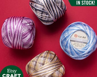 May include: Four balls of YarnArt Tulip thread in purple, blue, black-and-white, and gold-and-brown variegated colours. The blue ball features a label with the text YarnArt TULIP, 50 g / 1.76 oz, 250 m / 273 yds. Text on image: ALL COLORS IN STOCK!