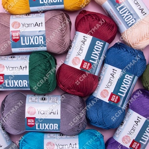 May include: Assortment of yarn skeins in various colors, including red, blue, green, gray, beige, and teal. Each skein is labeled "YarnArt LUXOR GIZA COTTON" with the brand name and website address.