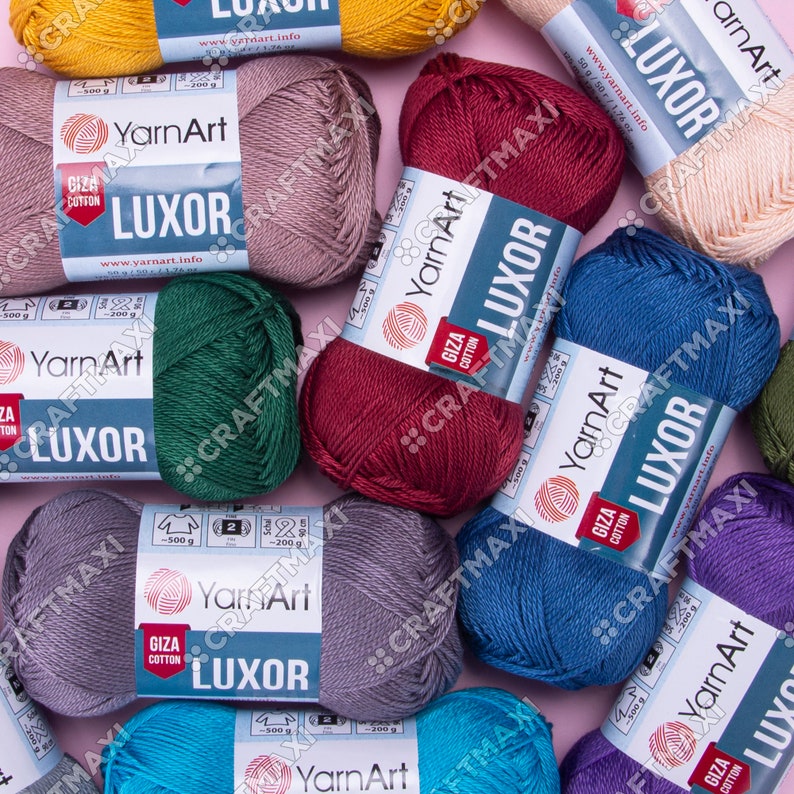 May include: Assortment of yarn skeins in various colors, including red, blue, green, gray, beige, and teal. Each skein is labeled "YarnArt LUXOR GIZA COTTON" with the brand name and website address.