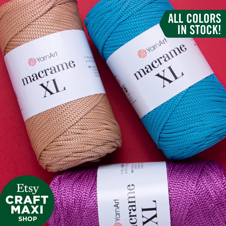 May include: Three spools of macrame cord in beige, teal blue, and purple. The spools are labeled "YarnArt macrame XL".