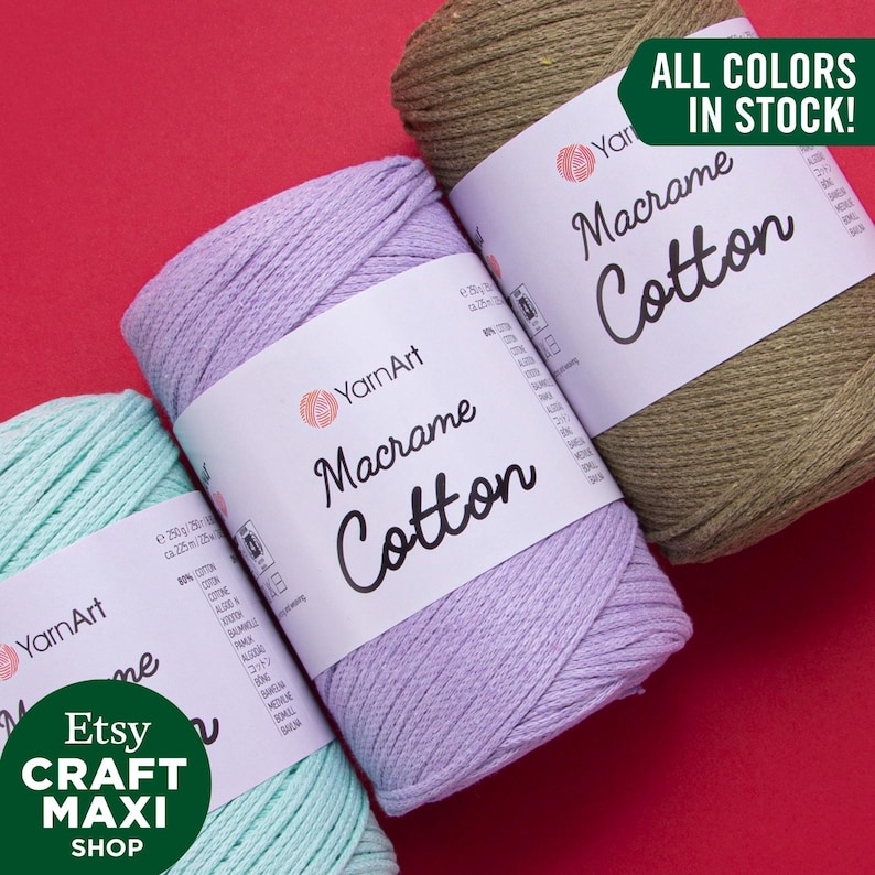 Op de afbeelding: Drie spoelen macram&eacute; katoenen garen in lavendel, groen en bruin. De spoelen zijn gelabeld "YarnArt Macrame Cotton". De tekst "ALL COLORS IN STOCK!" staat in een groene box.